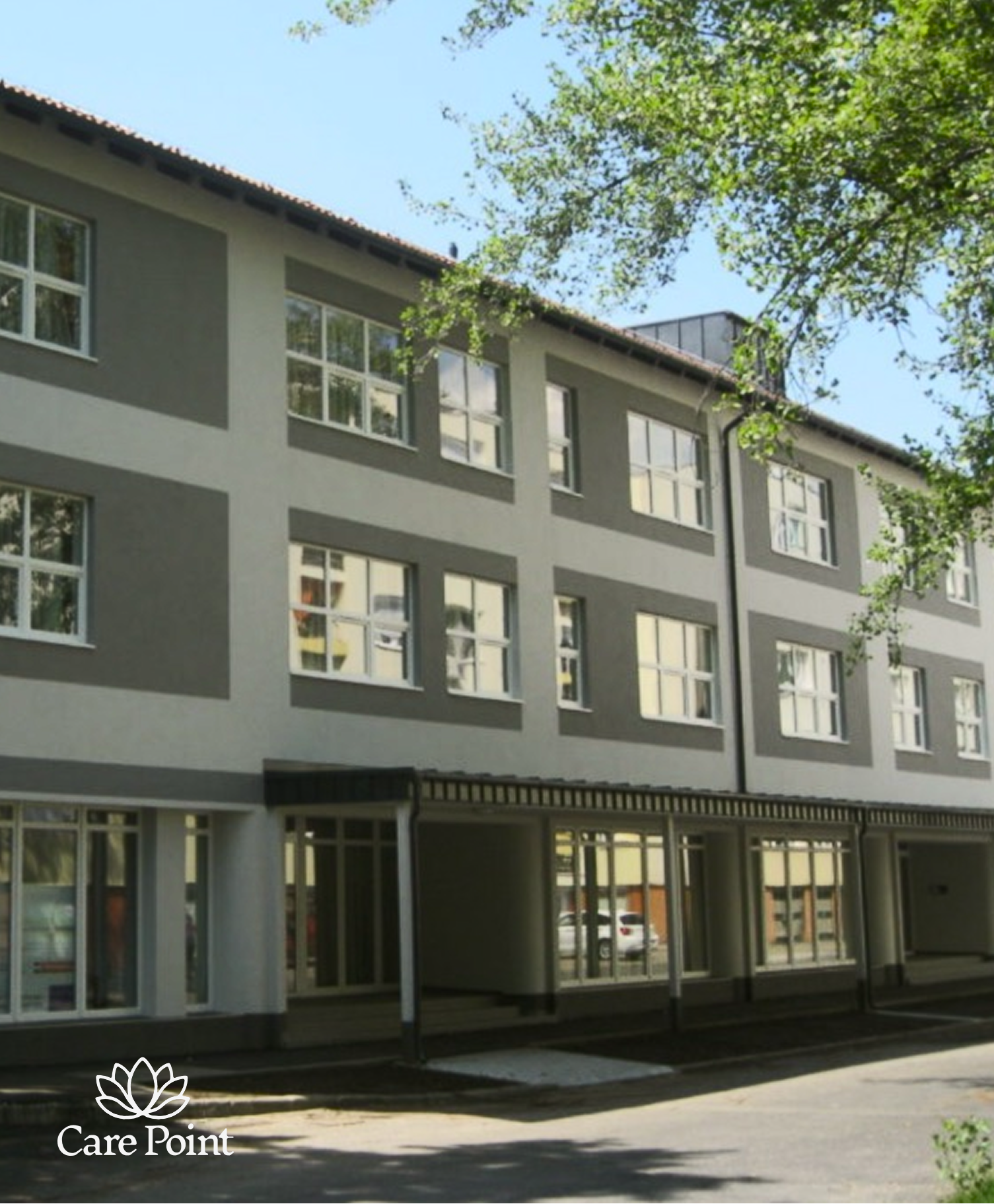 Reklámtábla a Care Point logóval, háttérben lakóház